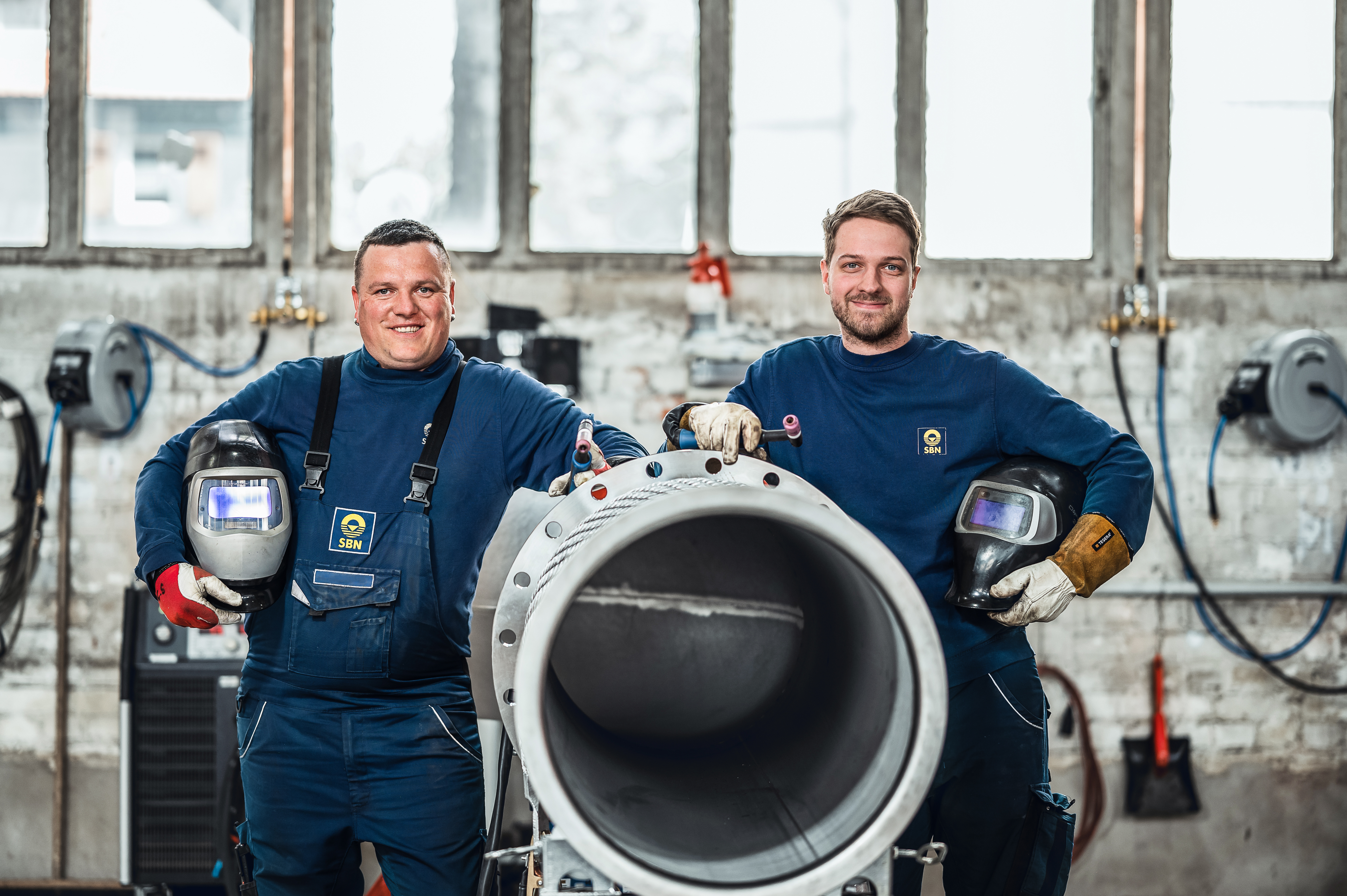 Starkes Team aus zwei Kollegen, die stolz ein fertiges Edelstahlbauteil präsentieren